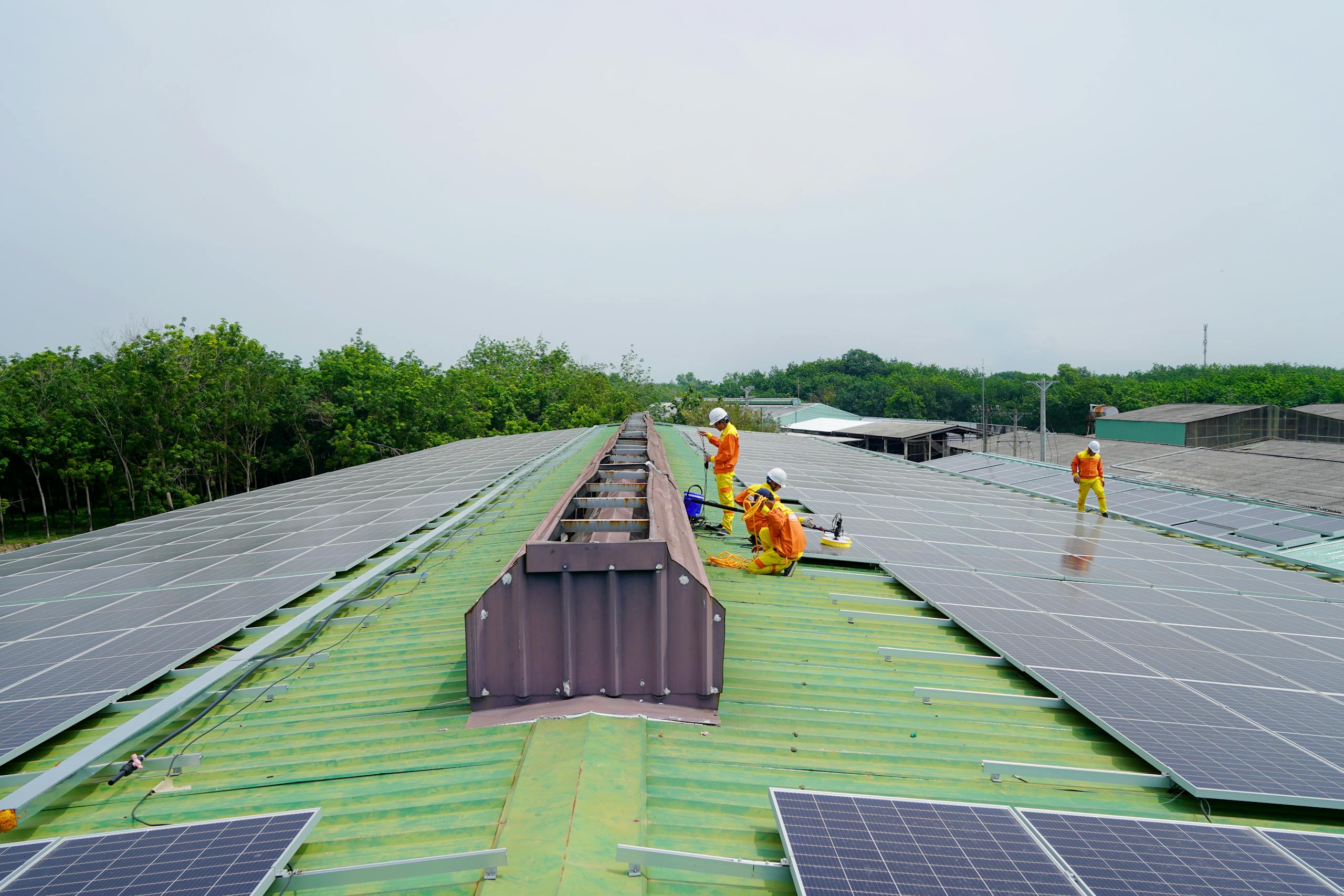 Team installing solar panels on a large rooftop under a clear sky, promoting renewable energy.